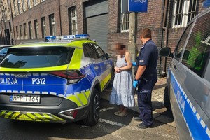 na zdjęciu policjant z zatrzymaną przy radiowozach