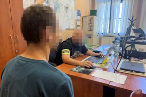na zdjęciu widoczny policjant siedzący przy biurku , który przesłuchuje siedzącego obok zatrzymanego sprawcę kradzieży