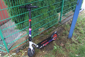 na zdjęciu hulajnoga elektryczna oparta o płot