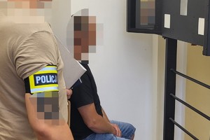 na zdjęciu policjant przy zatrzymanym siedzącym na krześle