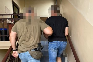 na zdjęciu policjant prowadzi zatrzymanego schodami