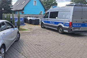 na zdjęciu radiowóz policyjny i samochód osobowy na podjeździe do posesji