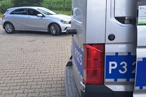 na zdjęciu fragment radiowozu, a za nim samochód osobowy
