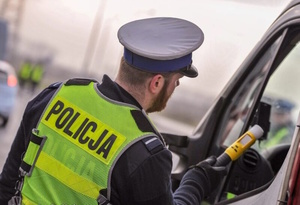 na zdjęciu policjant z alkomatem przy samochodzie