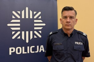 na zdjęciu dzielnicowy Mazur przy banerze z napisem policja