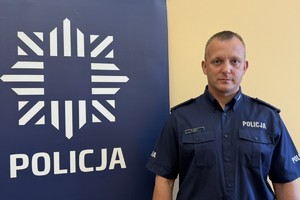na zdjęciu dzielnicowy Cieślik przy banerze z napisem policja