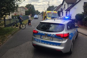 na zdjęciu radiowozy i karetka pogotowia na jezdni, obok osoby