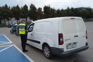 na zdjęciu policjant przy kontrolowanych samochodzie
