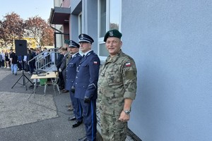 na zdjęciu policjanci i wojskowy pod budynkiem szkoły