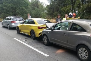 na zdjęciu trzy samochody na jezdni z uszkodzeniami, obok nich osoby i strażacy