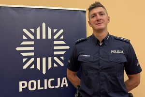 dzielnicowy przy banerze z napisem policja