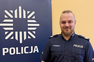 dzielnicowy Huras przy banerze z napisem policja