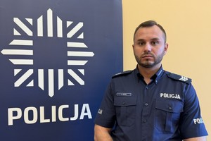 na zdjęciu dzielnicowy Duda przy banerze z napisem policja