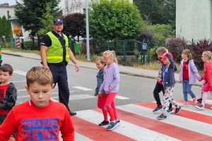 na zdjęciu policjant z dziećmi na przejściu dla pieszych