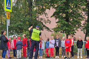 na zdjęciu policjant z dziećmi na przejściu dla pieszych