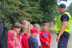 na zdjęciu policjant z dziećmi na przejściu dla pieszych