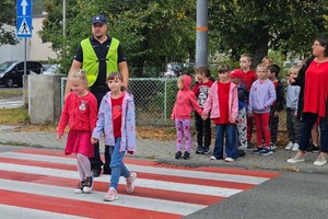 na zdjęciu policjant z dziećmi na przejściu dla pieszych
