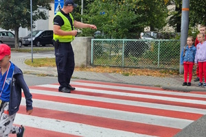 na zdjęciu policjant z dziećmi na przejściu dla pieszych