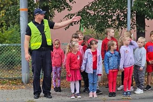 na zdjęciu policjant z dziećmi na przejściu dla pieszych