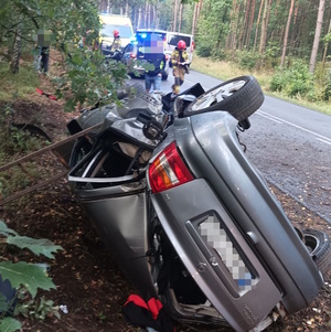 na zdjęciu samochód w rowie, obok pojazdy służb i inne osoby