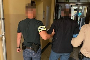 na zdjęciu policjanci z zatrzymanym w korytarzu komendy