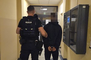 na zdjęciu policjant z zatrzymanym w korytarzu komendy