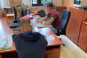 na zdjęciu przy biurku policjant i zatrzymany