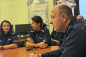 na zdjęciu policjant i policjantki przy stole w trakcie odprawy