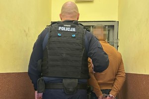 na zdjęciu policjant z zatrzymanym w pomieszczeniu