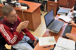na zdjęciu mężczyzna w czerwonej bluzie przy biurku