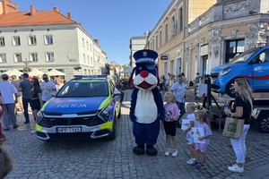 na zdjęciu policyjna maskotka sznupek na płycie tarnogórskiego rynku w trakcie zlotu pojazdów zabytkowych w towarzystwie różnych osób robiący zdjęcia