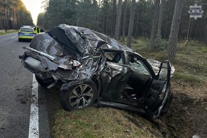Na zdjęciu rozbity pojazd w rowie za nim radiowóz i policjant