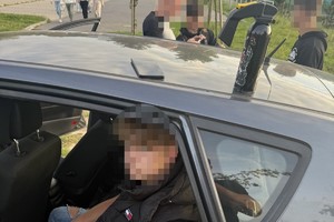 na zdjęciu osoba w aucie, na dachu butla z gazem