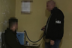 na zdjęciu policjant z nieletnim przy alkomacie