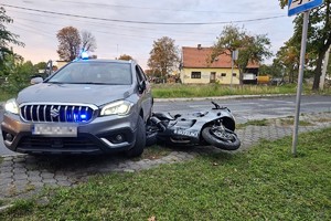 na zdjęciu nieoznakowany radiowóz, obok niego na jezdni leżący motocykl