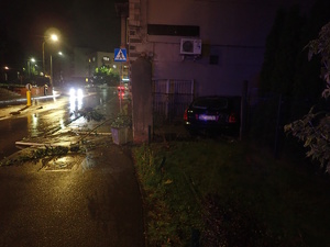 na zdjęciu samochód z uszkodzeniami przy budynku i uszkodzonym ogrodzeniu posesji