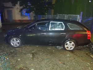 na zdjęciu samochód z uszkodzeniami przy budynku i uszkodzonym ogrodzeniu posesji
