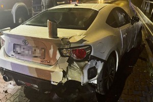 na zdjęciu biały samochód z uszkodzeniami na chodniku