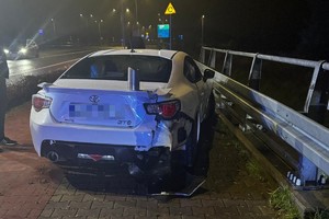 na zdjęciu biały samochód z uszkodzeniami na chodniku