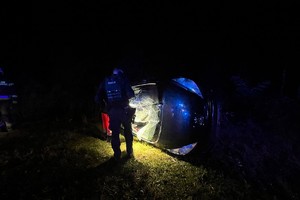 na zdjęciu policjant przy samochodzie wywróconym na boku
