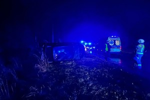 na zdjęciu samochód na boku, obok karetka i strażak