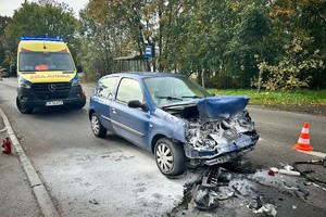 na zdjęciu nadpalony samochód na jezdni, za nim karetka pogotowia
