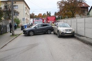 na zdjęciu samochody na jezdni i osoby obok