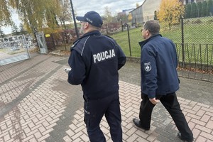 na zdjęciu policjant i kapelan policji przed bramą na cmentarz