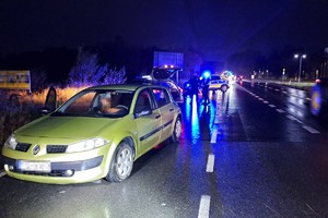 na zdjęciu samochód na jezdni, za nim policjanci i radiowóz oraz inne samochody