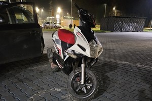 na zdjęciu nieoznakowany radiowóz, obok motorower