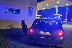 na zdjęciu nieoznakowany radiowóz, obok motorower