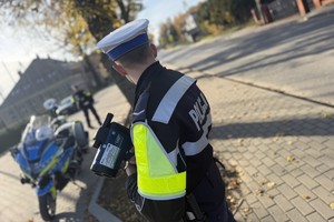 na zdjęciu policjant przy drodze obok policyjnego motocykla