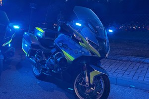 na zdjęciu policyjny motocykl z włączonymi niebieskimi światłami