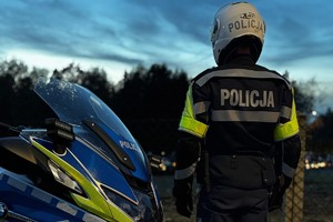 na zdjęciu policjant przy motocyklu obok cmentarza